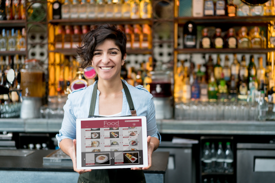 iStock-525498662 -- Woman Holding Tablet in front of Bar -- XXL